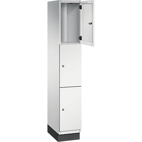 Armoire blanche et haute avec deux portes et une porte ouverte. Sur un socle noir.