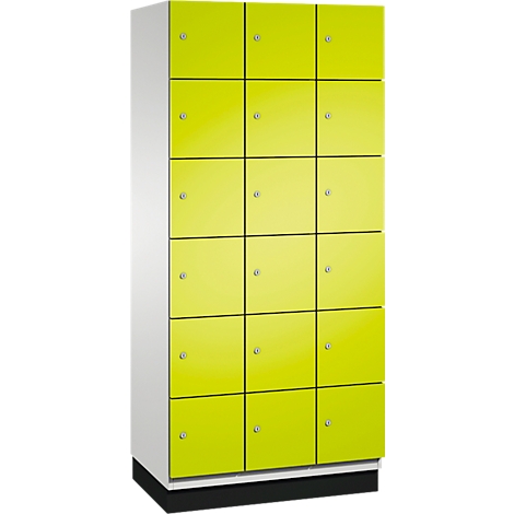 Une haute armoire jaune avec 15 portes. Les portes ont des poignées argentées. L'armoire repose sur un socle noir.