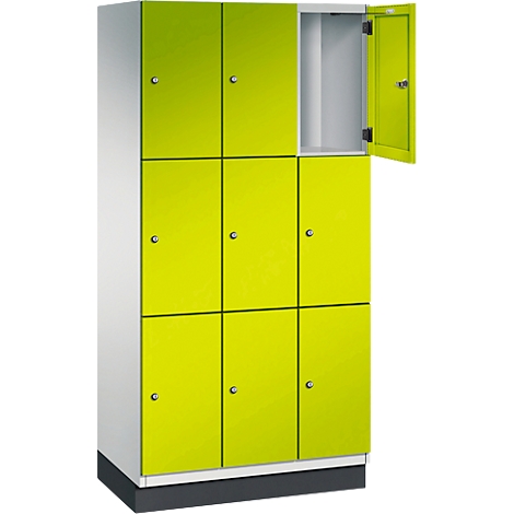Armoire avec portes jaune-vert, une porte est ouverte. L'armoire repose sur un socle gris.
