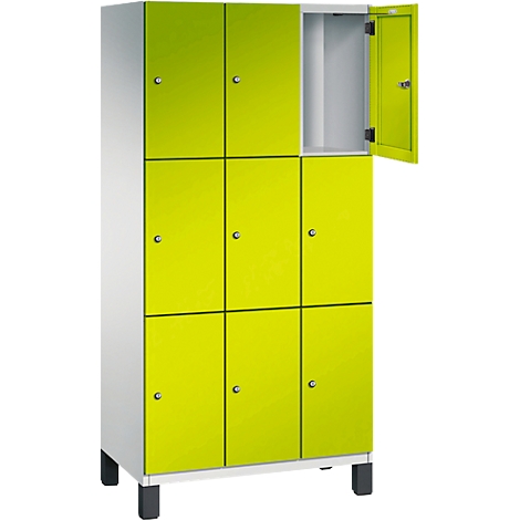 Armoire avec plusieurs compartiments, portes vert clair, une porte ouverte.