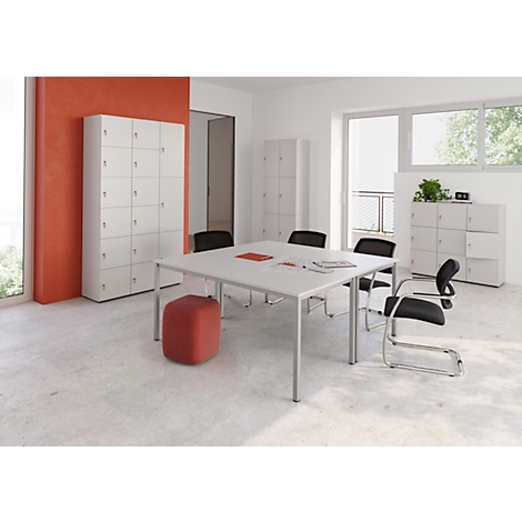 Un bureau lumineux et moderne avec table, chaises et armoires. Un tabouret rouge est à côté. Fenêtres avec lumière du jour.