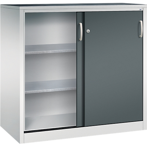 Armoire métallique claire avec portes coulissantes, un côté ouvert avec étagères, l'autre gris foncé fermé.