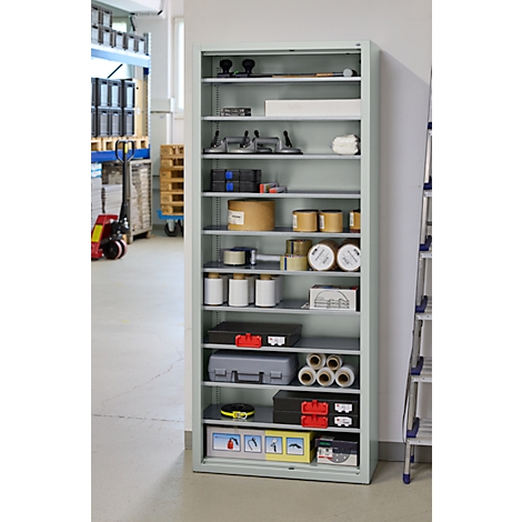 Armoire métallique grise avec outils, rouleaux de papier, conteneurs et boîtes. Dans un atelier.