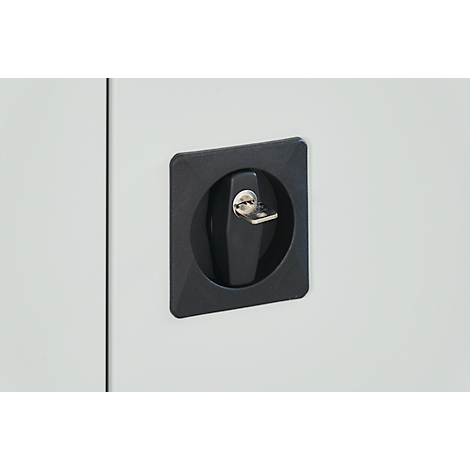 Gros plan d'une poignée de placard noire avec une clé dans une porte métallique.