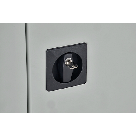Gros plan d'une serrure noire avec clé dans une porte grise.
