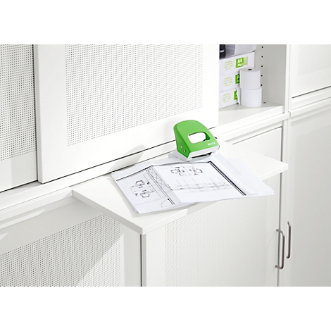 Un tampon vert est posé sur une extension blanche sur laquelle se trouve un plan de construction. Dans le fond, une armoire blanche.