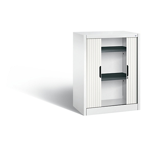 Armoire blanche avec volet roulant, deux étagères et poignées noires. L'armoire est posée sur un fond blanc.