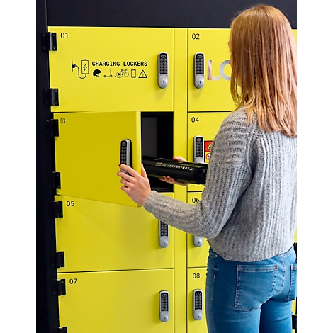 Jeune femme ouvrant un casier jaune. Sur le casier, il est écrit "CHARGING LOCKERS". Elle tient un objet noir.