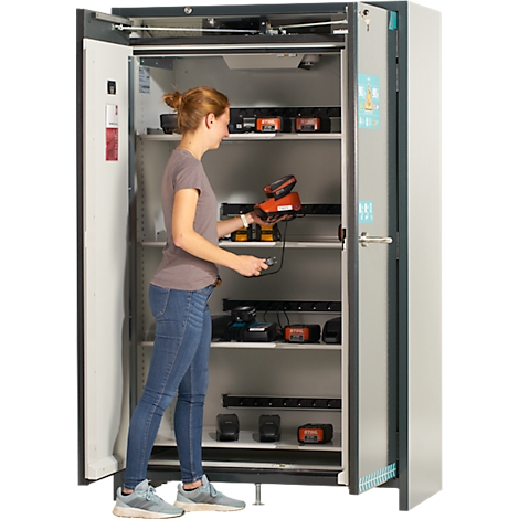 Eine Frau öffnet einen Schrank mit Werkzeug, in dem sich aufgeladene Werkzeuge befinden.