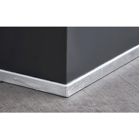 Corner with dark gray wall, baseboard, and wooden floor.