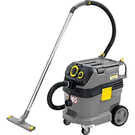 Aspirateur industriel Kärcher gris et jaune avec tube d'aspiration et brosse sur fond blanc.