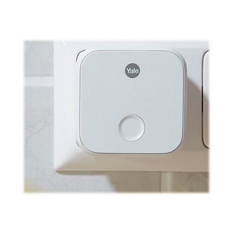 Ein weißer, quadratischer Yale WLAN-Bridge-Adapter eingesteckt in einer Wandsteckdose.