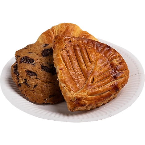 Trois pâtisseries sur une assiette en papier blanche : un biscuit aux pépites de chocolat, un croissant et un morceau de pâte feuilletée.