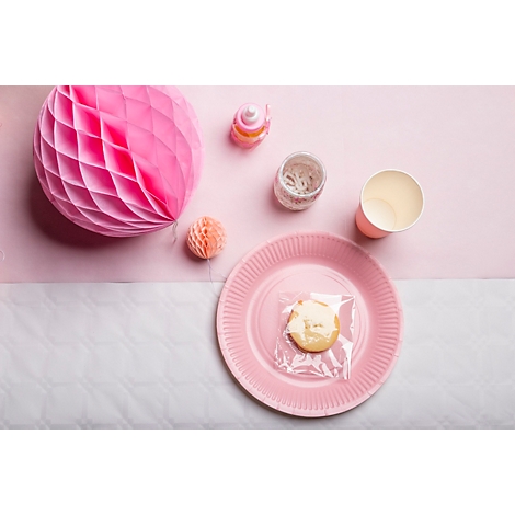 Vue aérienne d'une décoration de table rose. Un cookie dans du papier d'aluminium sur une assiette, à côté de tasses, de décorations.