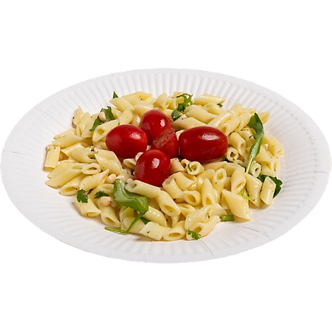 Pâtes penne avec tomates et herbes sur une assiette en papier blanche.