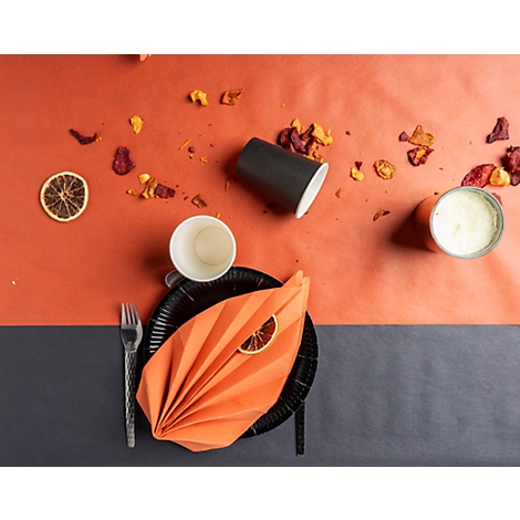 Vue de dessus de la table dressée : assiette noire avec serviettes, tasses, citrons verts, fourchette et collations.