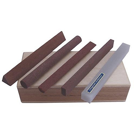 Cinq pierres à aiguiser de différentes formes et tailles sur une base en bois, une blanche avec texte.