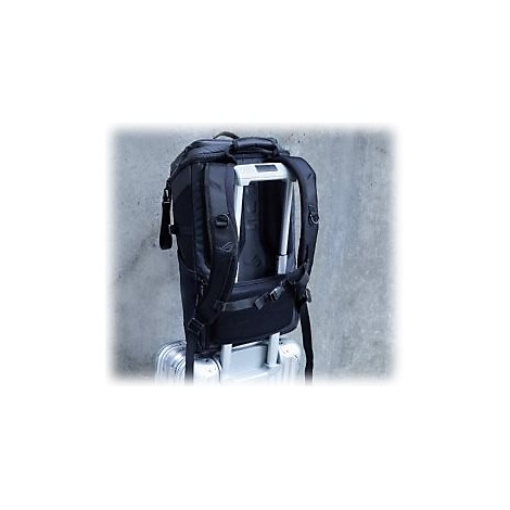 Schwarzer Rucksack auf einem silbernen Koffer, vor grauem Hintergrund. Die Schultergurte sind sichtbar.