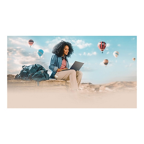 Eine Frau mit Laptop auf einem Felsen mit Heißluftballons im Hintergrund.