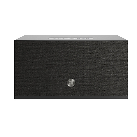 Haut-parleur gris foncé sur fond blanc, rectangulaire avec revêtement en tissu, logo argenté et panneau de commande.