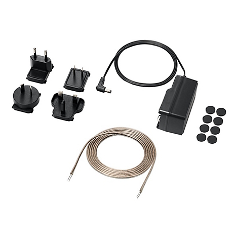 Produkt-Set auf weißem Hintergrund: Mehrere Stecker, Netzteil, Kabel und runde Pads.