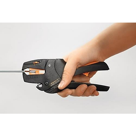 Hand die een zwarte krimptang met oranje elementen en een kabel vasthoudt, tegen een witte achtergrond.
