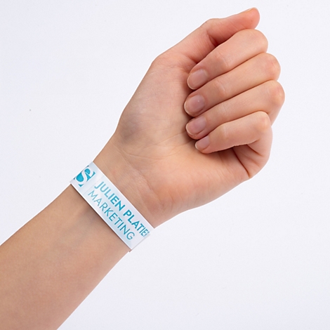 Ein weißes Einlassband mit blauem Aufdruck am Handgelenk einer Person. Text: 100 Einlassbänder, klimaneutral.