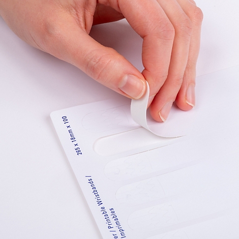 Hand löst ein weißes, selbstklebendes Einlassband von einem A4-Druckbogen.
