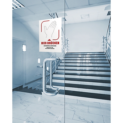 Porte en verre transparente avec un panneau indiquant "Appuyer ici". Un escalier en arrière-plan.