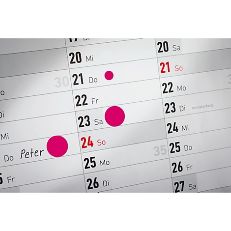 Close-up van een kalender met roze markeringen op verschillende data. De 24e is rood gemarkeerd.