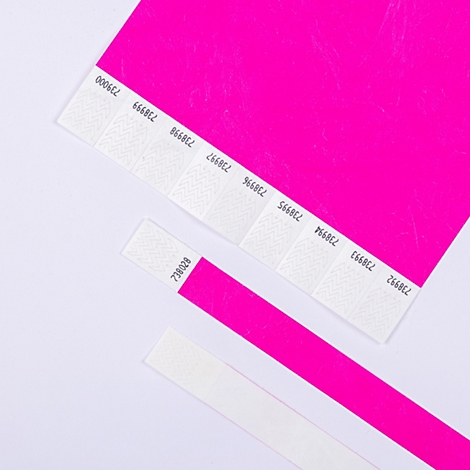 Bracelets d'identification rose fluo avec fermeture adhésive blanche et numérotation séquentielle sur fond clair.