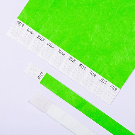 Mehrere neon-grüne Eintrittsbänder aus Papier mit fortlaufender Nummerierung auf weißem Hintergrund.