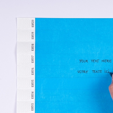 Hellblaues Armband wird mit einem Stift beschriftet, mit Hinweistext 'Beschriftbar mit Permanent-Marker'.