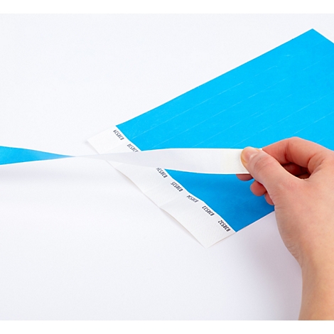 Een hand trekt een witte beschermstrip van een felblauw polsbandje.