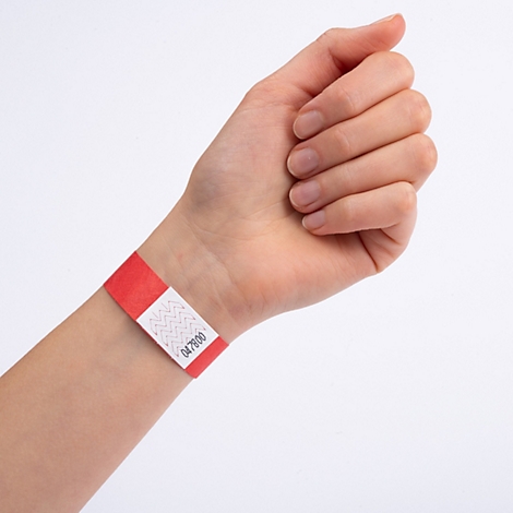 Een rood polsbandje met een wit vlak en het nummer 047800 om een pols.
