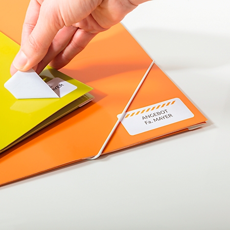 A hand peels a sticker from a yellow folder. Stickers with text 'Angebot Fa. Mayer' on an orange folder.