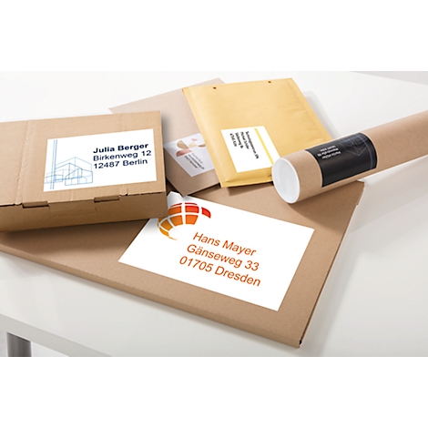 Various packages and envelopes, labeled with address labels, are lying on a white surface.