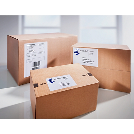 Drei braune Kartons mit weißen Etiketten, gestapelt. Auf den Etiketten sind Informationen und Barcodes zu sehen.