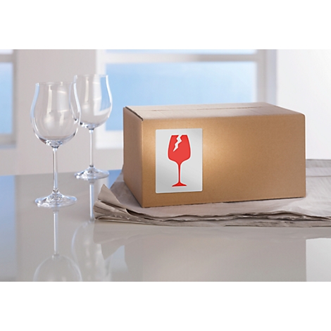 Two wine glasses and a cardboard box with a fragile symbol on a table.