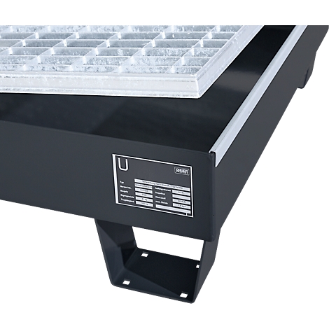 Gros plan d'un bac noir avec une grille. Un panneau avec du texte est visible sur le devant.