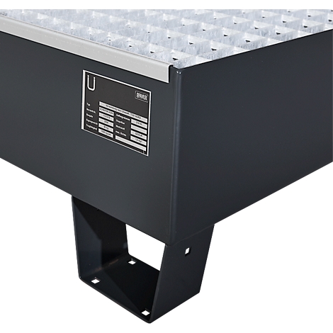 Conteneur en métal gris, vue détaillée. Une grille sur le dessus, une plaque signalétique avec des lettres sur le côté. Pied en métal noir comme support.