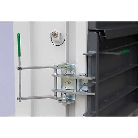 Detailed view of a metal latch with a green handle attached to a gray metal wall.