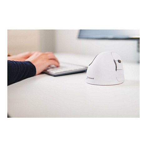 Weisse Vertikalmaus, neben Person die auf Tastatur tippt, auf weissem Tisch. Im Hintergrund Monitor.