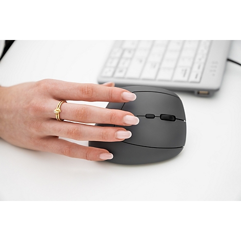 Hand mit Ring, die eine graue ergonomische Maus bedient, Tastatur im Hintergrund.