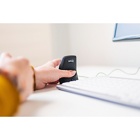 Een hand die een ergonomische muis vasthoudt naast een toetsenbord op een witte tafel.