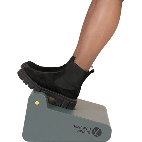 Pieds dans des bottes noires sur un piédestal gris avec logo de la marque.