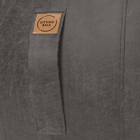 Primer plano de un asiento gris. Una pequeña etiqueta marrón que dice "SITTING BALL" está cosida.