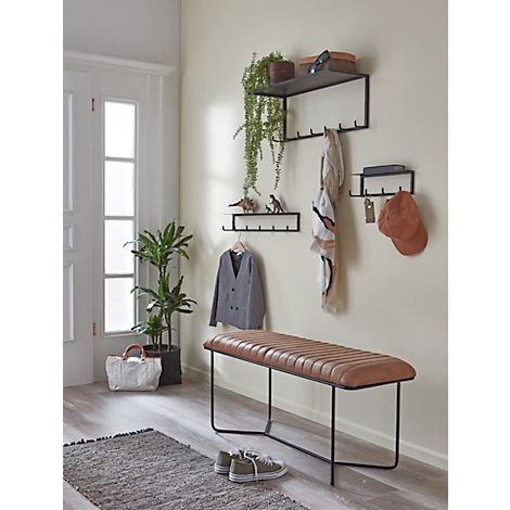 Hall d'entrée avec un banc, des porte-manteaux, des plantes et de la décoration. Des chaussures sont visibles au premier plan.