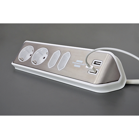 Prise multiple argentée avec trois prises, deux ports USB et un bord blanc. Un câble blanc est branché.