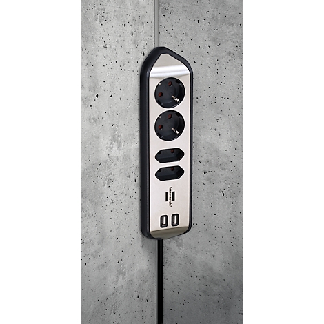 Multiprise grise et noire avec deux prises, deux ports USB, sur un mur en béton.